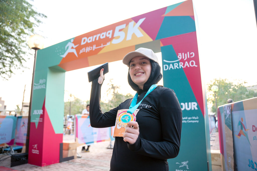 Darraq 5k finisher holding the medal at the finish line