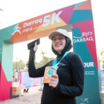 Darraq 5k finisher holding the medal at the finish line