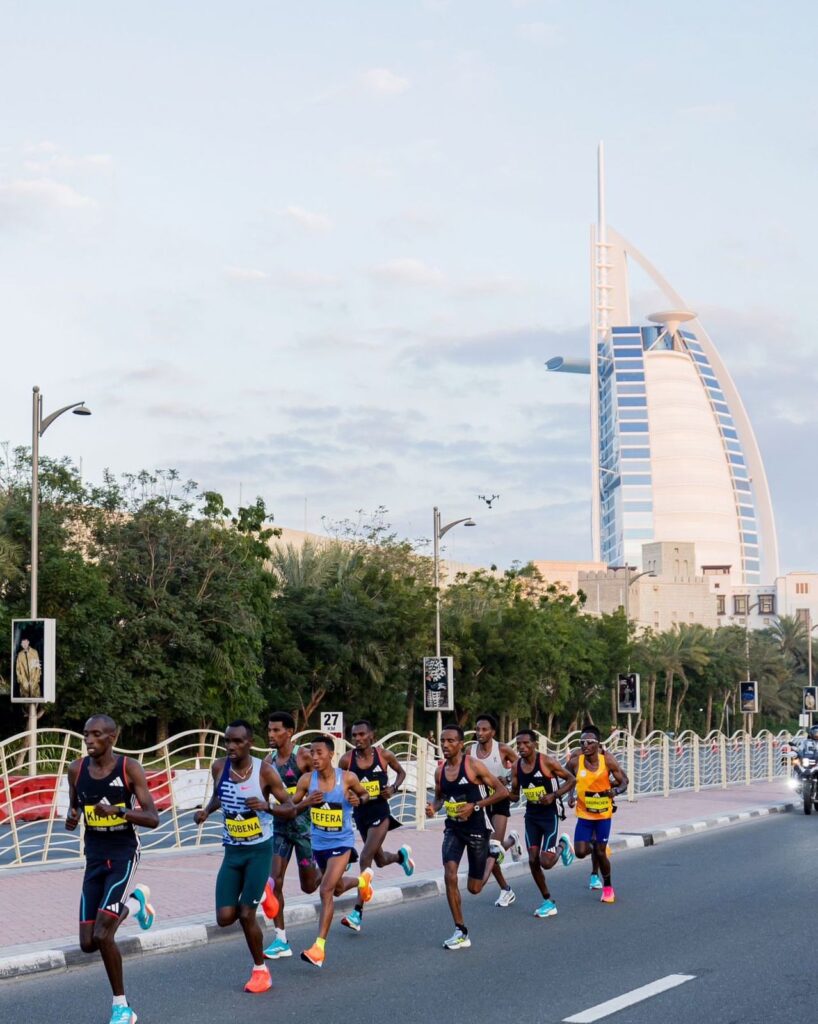 People racing at the Dubai Marathon behind Burj Al Arab